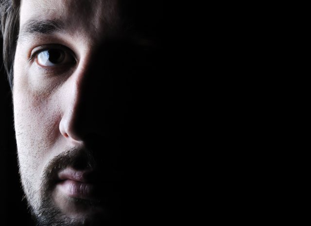 Low-key portrait - half face - sad and angry looking man